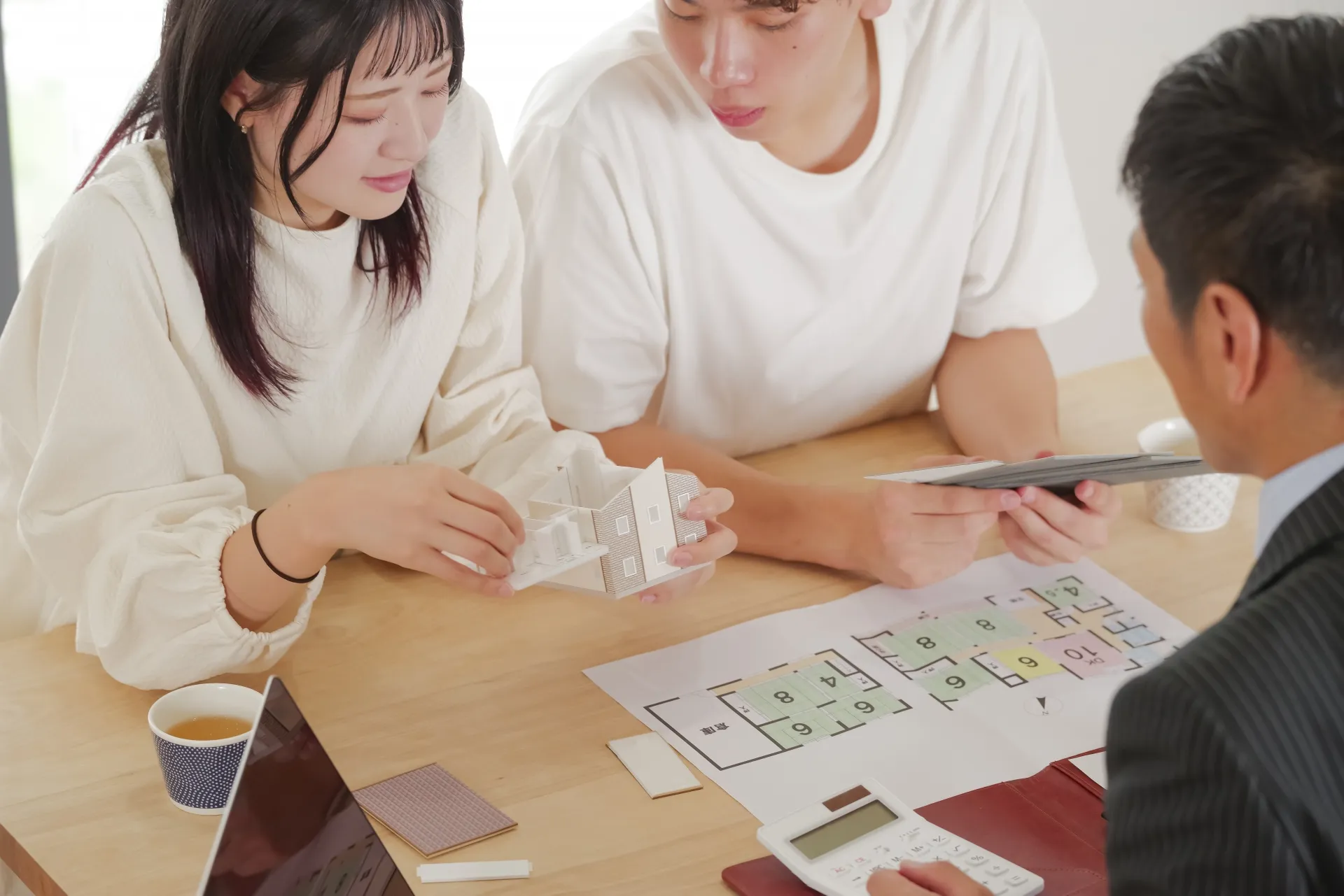 家の模型を見ながら戸建てを検討する若い夫婦